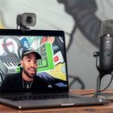 Webcam Logitech StreamCam sur un ordinateur portable à côté d'un microphone, avec un streamer masculin à l'écran.