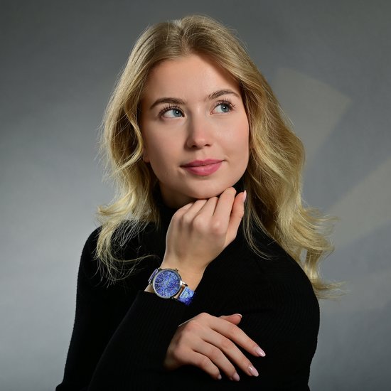 Jong blond model met zwarte coltrui, draagt zilverkleurig horloge met blauw mozaïekpatroon.