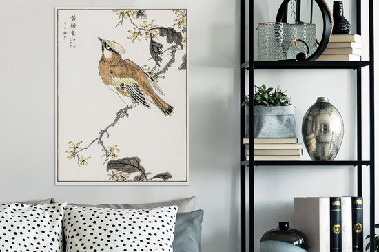 Une estampe japonaise d'un oiseau sur une branche fleurie, accrochée au-dessus d'un canapé à côté d'une étagère métallique.