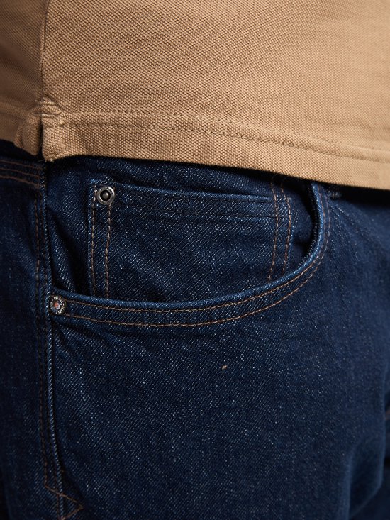Donkerblauwe jeans met een klein rond merkembleem op de coin pocket.