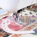 Een naaipatroon liniaal naast een naaimachine die op patchwork stof naait.