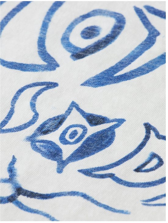 Close-up van een witte stof met een blauwe, losse aquarelprint van een abstract figuur.