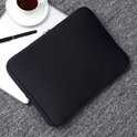 Housse d'ordinateur portable noire sur un tapis gris à côté d'un ordinateur portable, avec une tasse de café et un stylo