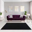 Tapis shaggy noir dans un salon avec un canapé violet, trois tableaux et un lampadaire.
