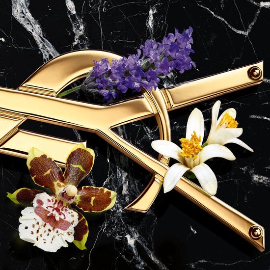 Gouden YSL-logo met lavendel en bloemen op een zwarte marmeren achtergrond.