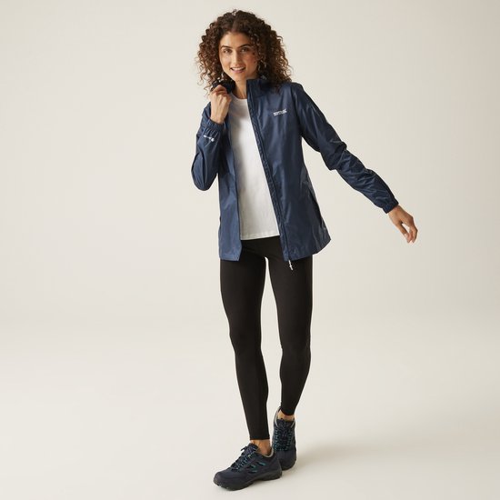 Vrouw met krullend haar in een donkerblauwe, waterdichte jas met capuchon en witte kleding eronder.