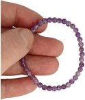 Hand houdt een armband vast van kleine, paarse amethistkralen.