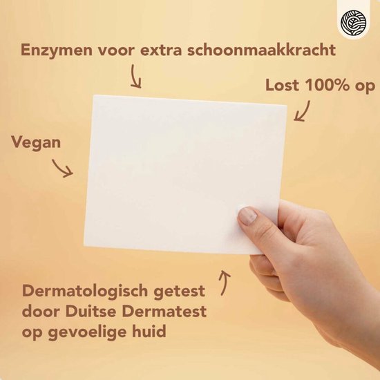 Hand toont witte wasstrip, met tekst 'Enzymen voor extra schoonmaakkracht', 'Lost 100% op', 'Vegan', 'Dermatologisch getest door Duitse Dermatest op gevoelige huid'.