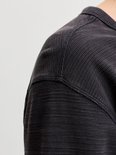 Detailopname van de schouderpartij en textuur van de antracietgrijze henley-top.