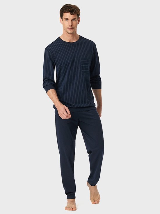 Model draagt een donkerblauwe, verticaal gestreepte pyjamaset met lange mouwen en borstzak.