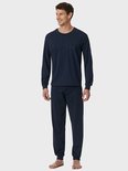 Model in donkerblauwe pyjamaset, bovenstuk met verticale strepen en borstzak, lange effen broek.
