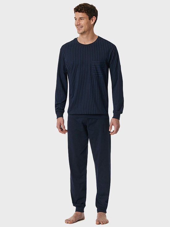 Model in donkerblauwe pyjamaset, bovenstuk met verticale strepen en borstzak, lange effen broek.