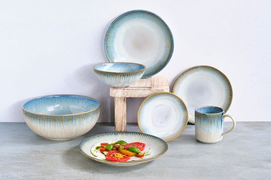 Serviesset met kommen, mokken en borden in blauw-bruine kleurstelling, opgesteld op houten blokken.