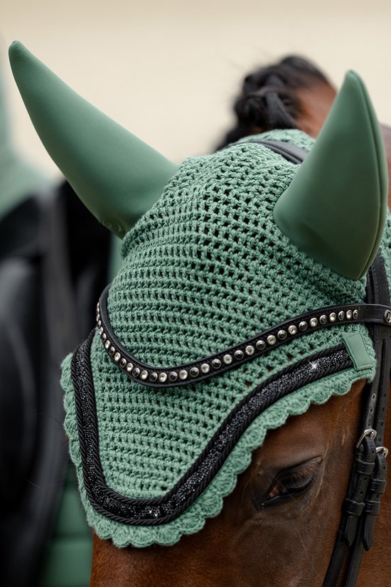 Groen gehaakt oornetje met zwarte strass-versiering op een bruin paard.