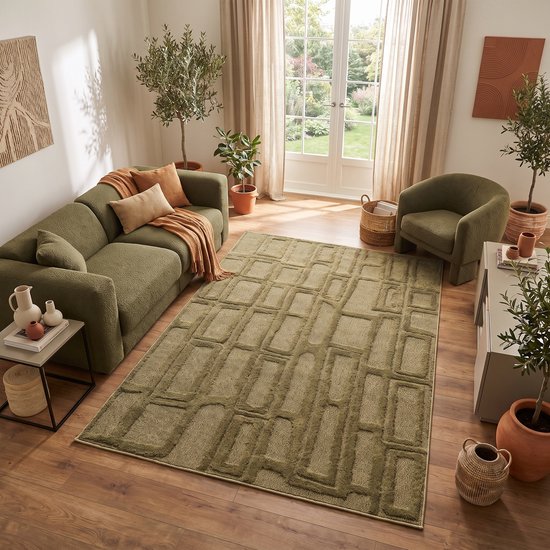 Olijfgroen vloerkleed in een modern ingerichte woonkamer met bank en fauteuil.