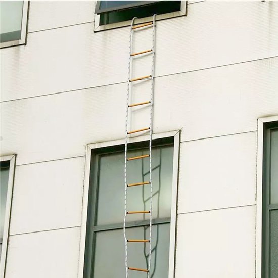 Een brandtrap met witte en blauwe touwen en houten sporten hangt langs een wit gebouw.