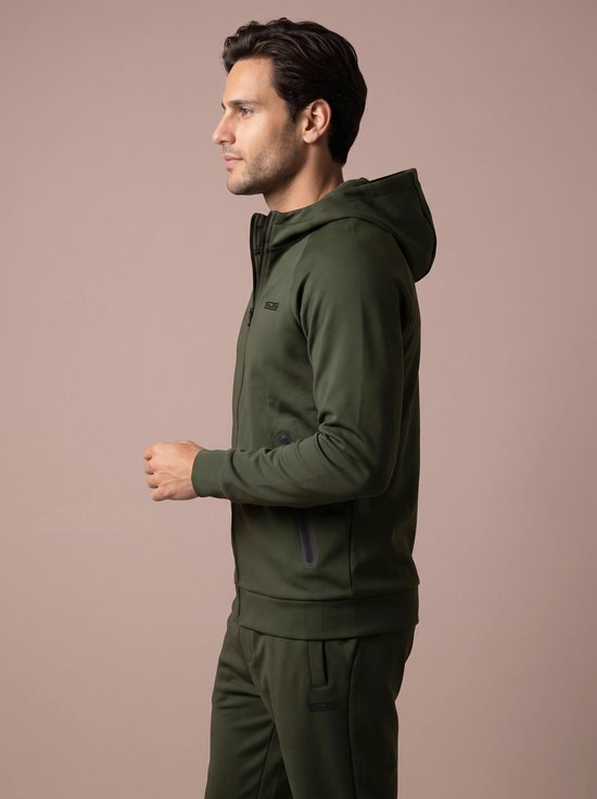 Man zijdelings gezien, draagt een olijfgroene hoodie met capuchon, rits en logo op de borst.