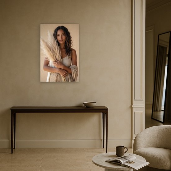 Canvas schilderij van een vrouw met pampasgras, hangend boven een smalle houten tafel in een hal.