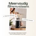 Vrouw demonteert VDN koffiezetter met meervoudig filtersysteem en houten handvat.