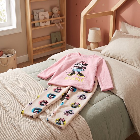 Roze koraalfleece Minnie Mouse pyjamaset met tekst MINNIE en een broek met Minnie-motief, plat neergelegd op een bed.