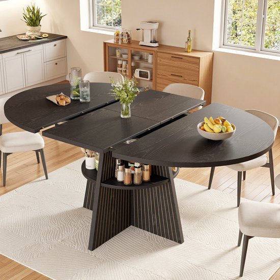 Zwarte, ronde uitschuifbare tafel met houten latten, opbergplank en vier beige stoelen in een keuken.