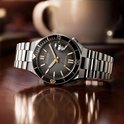 Citizen Tsuyosa horloge met zwarte wijzerplaat, goudkleurige wijzers en stalen band op een houten ondergrond.