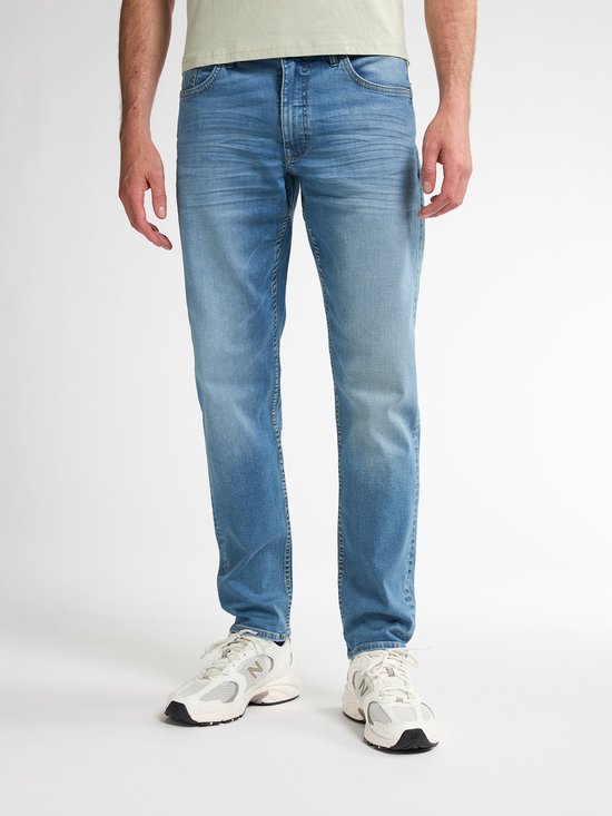 Man met lichtblauwe jeans met een regular tapered fit en beige sneakers.