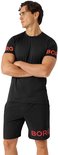 Man in petrolkleurig sportshirt en short, met zwarte tekst op de mouw.