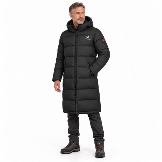 Man in een zwarte, gewatteerde Norlund winterparka met capuchon tot over de knie, gedragen met grijze broek en wandelschoenen.