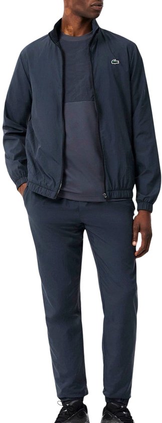 Model in marineblauw sportjack en bijpassende broek met Lacoste logo.