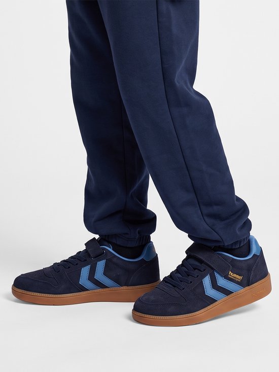 Hummel Handball Perfekt Cl Jr sneakers in donkerblauw suède met blauwe chevron-details, klittenband en bruine zool.