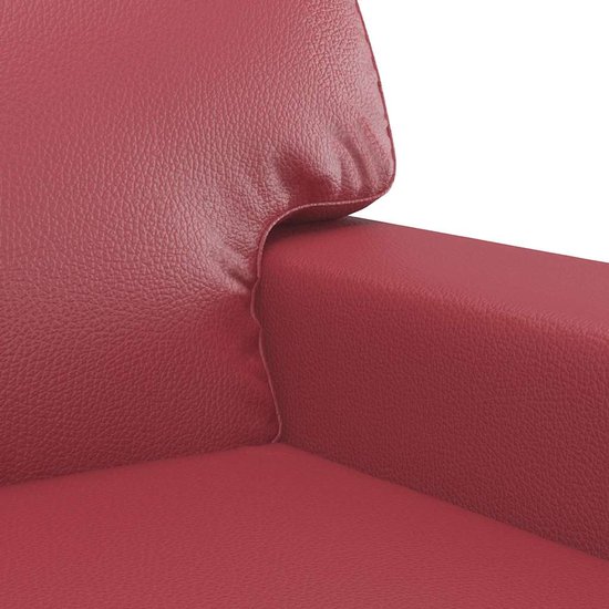 Gedetailleerd aanzicht van de armleuning en hoofdsteun van een wijnrode kunstleren fauteuil.