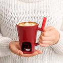 Rode keramische mok met een uitsparing voor een waxinelichtje en een rood handvat. De mok is gevuld met koffie.