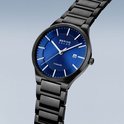 Zwart titanium herenhorloge met blauwe wijzerplaat, datumvenster en zilverkleurige indexen, schuin gefotografeerd.