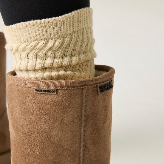Close-up van de bruine suède laars, met 'WATERPROOF' en 'REGATTA GREAT OUTDOORS' labels, en beige gebreide beenwarmers.