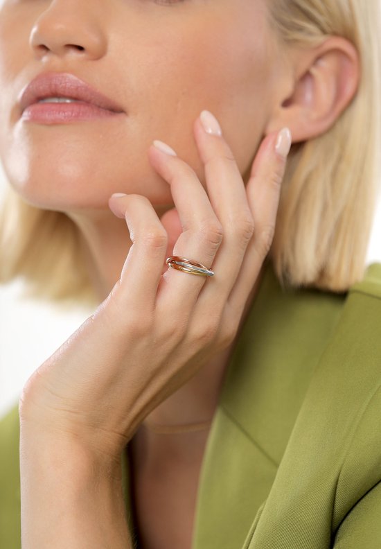 Close-up van een vrouw met een dri COLORS ring van zilver, goud en roségoud aan haar hand.
