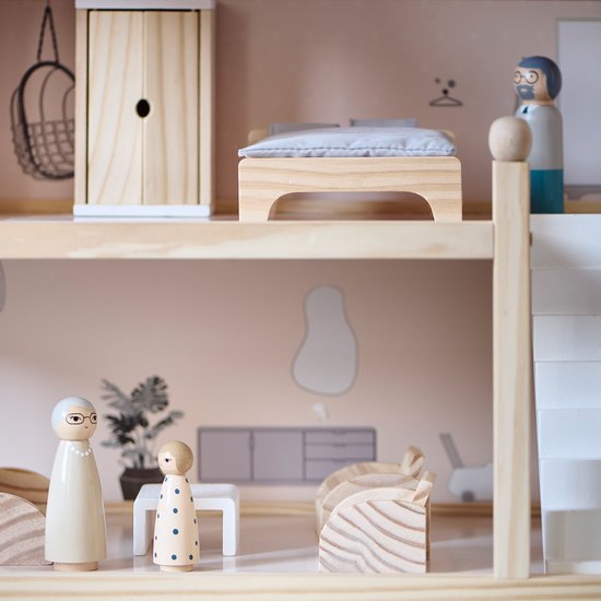 Interieur van een houten poppenhuis met bed, kast, en twee poppetjes. Eén met bril, één met stippen.