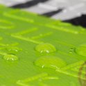 Close-up van een felgroen speelkleed met waterdruppels erop.