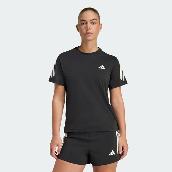 Vrouw in zwart sportshirt en -short met witte Adidas strepen, staand.