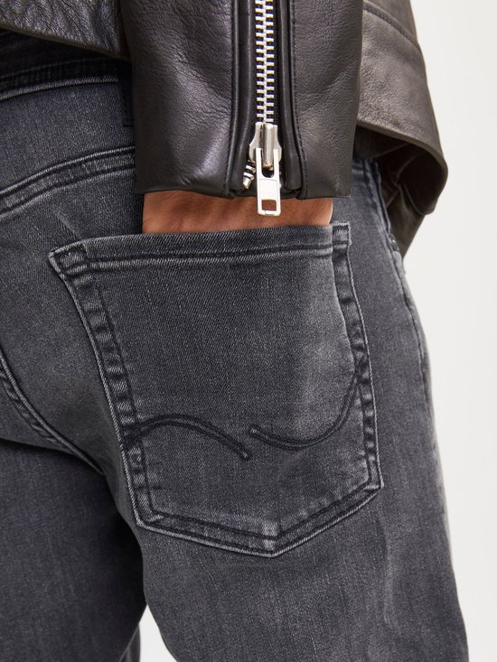 Sluit detail van een grijze jeans met een zak en een hand erin.