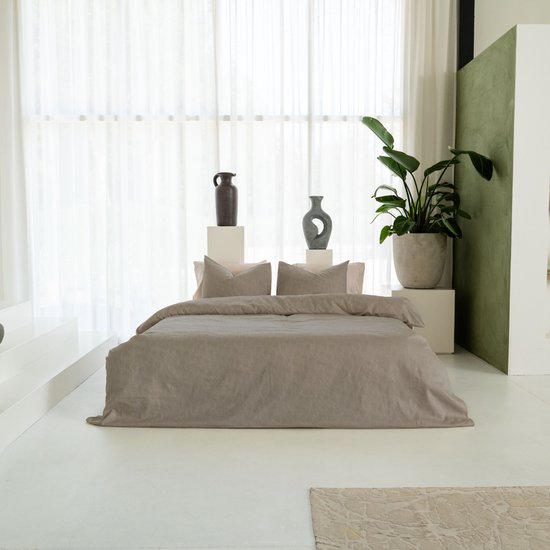 Compleet bed met beige dekbedovertrek, kussens en decoratie.