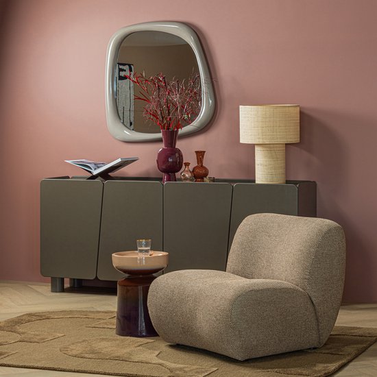 Lichtbruine chenille fauteuil in een woonkamer met een spiegel en kast.