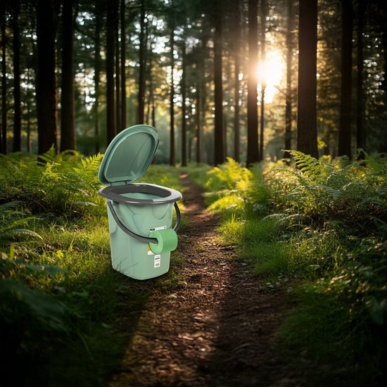 Groene campingtoilet emmer met deksel open en toiletpapier, staand op een bospad.
