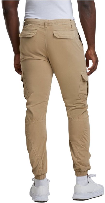 Man met beige cargo broek, achterkant zichtbaar, met zakken en elastische enkelbanden.