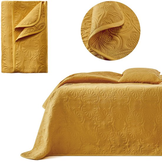 Gele sprei met cirkelvormig patroon, opgevouwen en uitgevouwen op een bed.