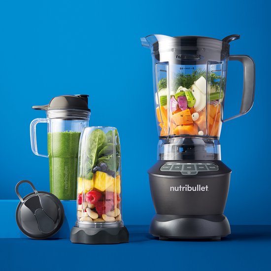 Nutribullet blender met beker met smoothie, kan vol groenten en fruit, op blauwe achtergrond.