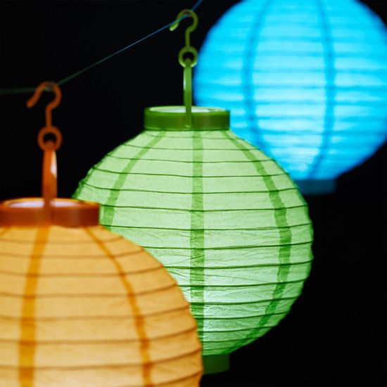 Drie verlichte papieren lampionnen in het oranje, groen en blauw, hangend aan een draad.