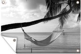 Tuinposters buiten Hangmat vastgeknoopt aan een palmboom bij een strand - zwart wit - 90x60 cm - Tuindoek - Buitenposter