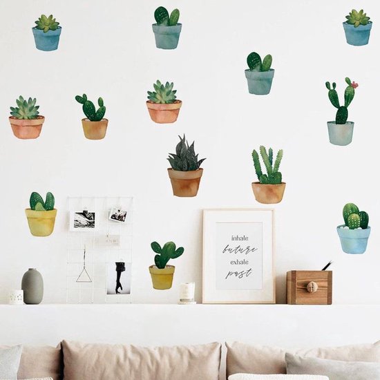 Stickers muraux représentant divers cactus et plantes succulentes en pots colorés, près d'un canapé.