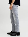 Zij-aanzicht van een man in een grijze jeans met rechte pijpen en zwarte gesp laarzen.